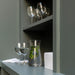 IKEA KARAFF glass carafe with greenery displayed on a grey shelf alongside two wine glasses green backdrop