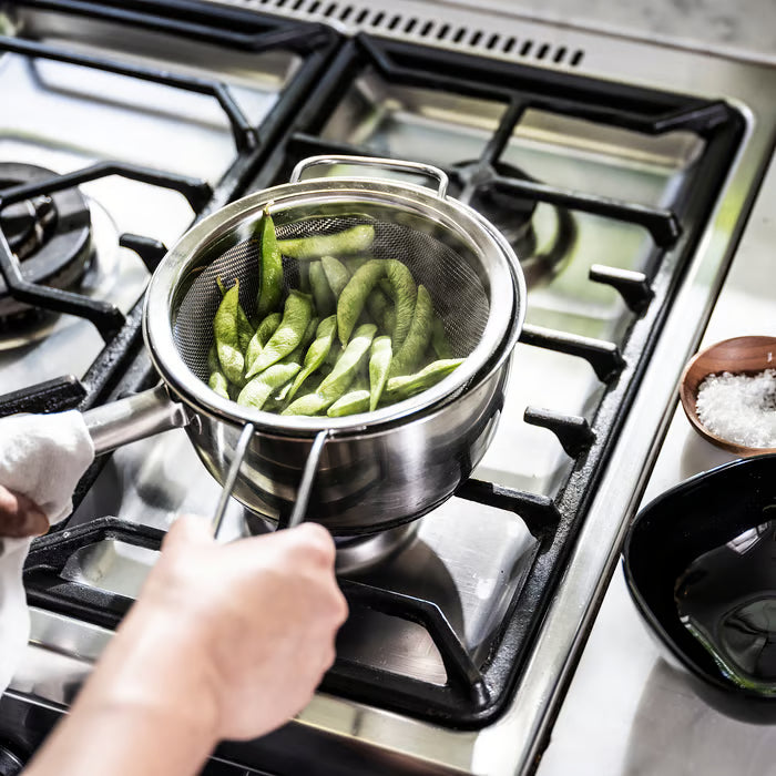 IKEA KLOCKREN colander in semi‑open position, being used as a steamer insert for vegetables
