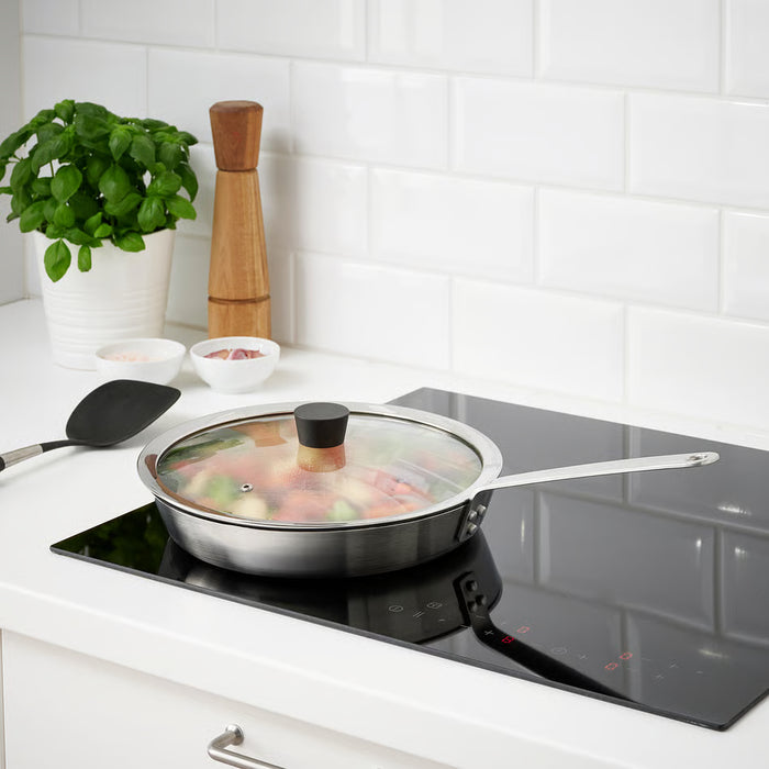 IKEA KLOCKREN glass pan lid placed on frying pan on induction cooktop in modern kitchen