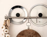 Two IKEA KLOCKREN glass pan lids hanging on kitchen hooks with wooden cutting board below