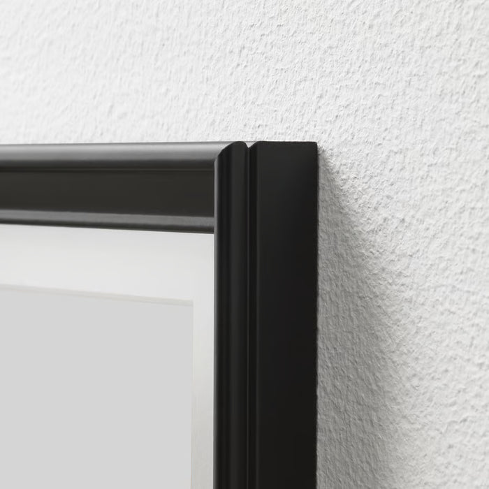 Close-up of IKEA KNOPPÄNG black frame mounted on white textured wall showing slim profile and edge detail