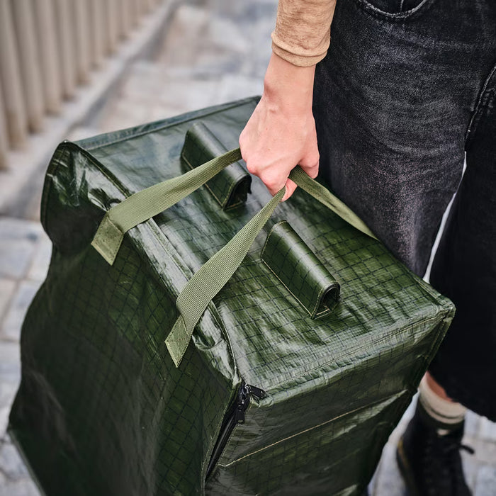 Person carrying IKEA KOMPISHÄNG green storage bag using adjustable shoulder straps