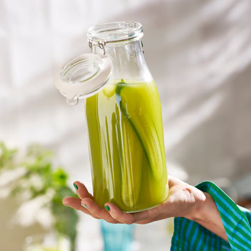 Hand holding IKEA KORKEN glass jar filled with green cucumber drink sealed with clamp lid