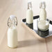 IKEA KORKEN glass bottles with stoppers arranged on wooden table with cup on metal serving tray
