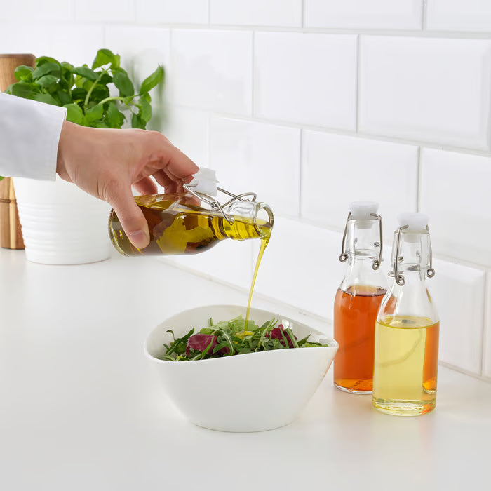 IKEA KORKEN glass bottle being used to pour oil over salad condiment serving table setting
