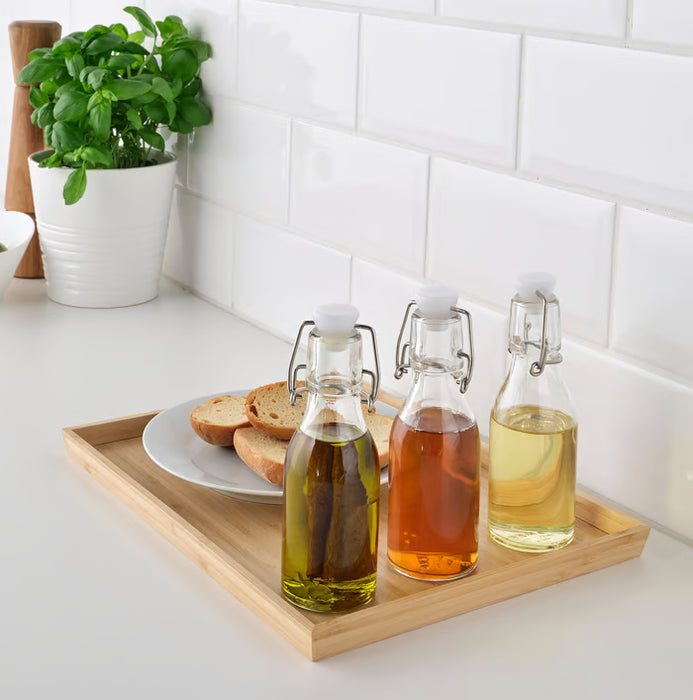 IKEA KORKEN glass bottles with stoppers on tray styled beside bread and indoor plant kitchen decor