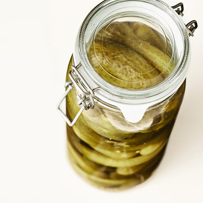  Close-up of IKEA KORKEN glass jar filled with pickles in brine showing airtight clasp seal detail