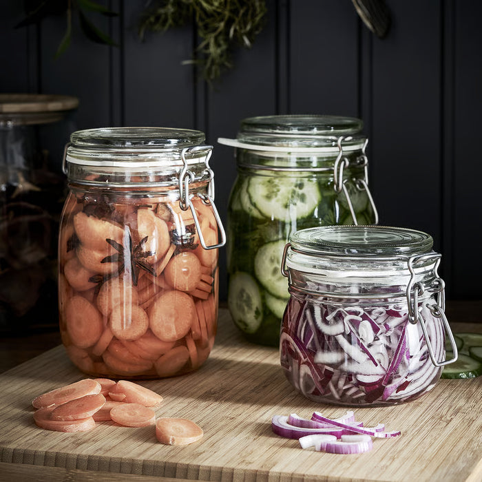 Three IKEA KORKEN glass jars filled with pickled vegetables and onions displayed on a wooden surface