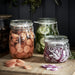 Three IKEA KORKEN glass jars filled with pickled vegetables and onions displayed on a wooden surface