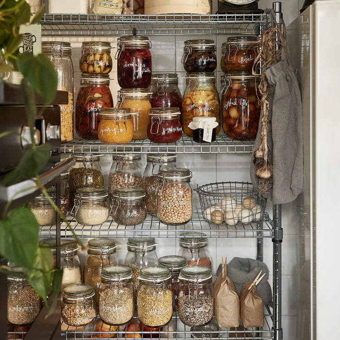 Kitchen shelves displaying IKEA KORKEN jars filled with pickles, jams, and grains in an organised pantry
