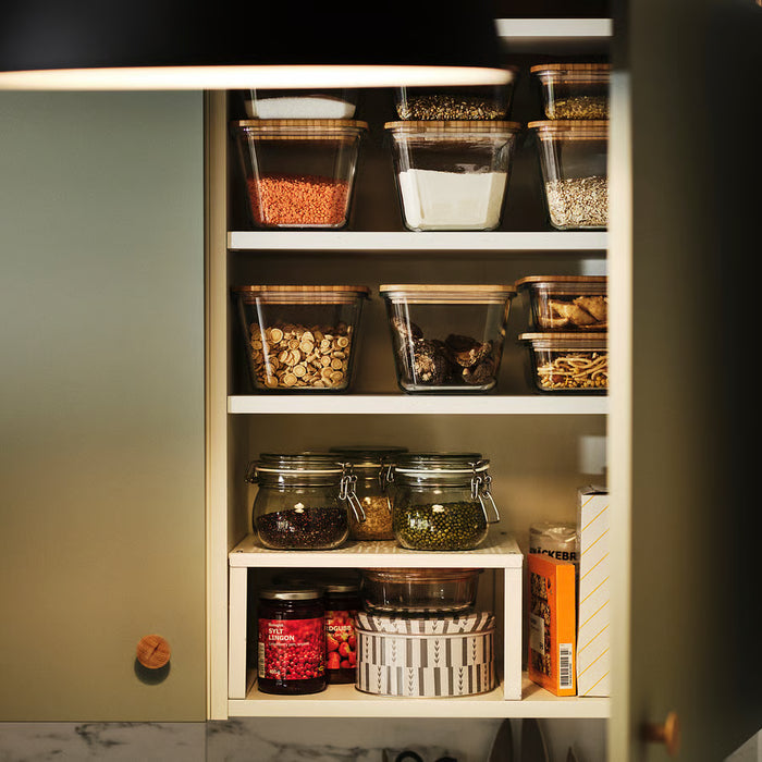Open cabinet with multiple IKEA KORKEN jars storing dry goods, pickles, and jams in an organised kitchen