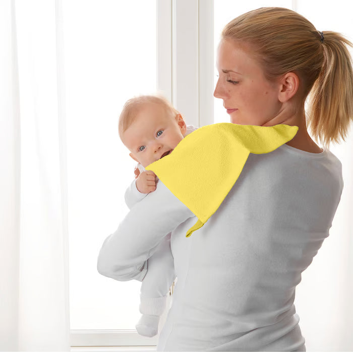 Parent holding baby with yellow IKEA KRAMA washcloth draped over shoulder after feeding