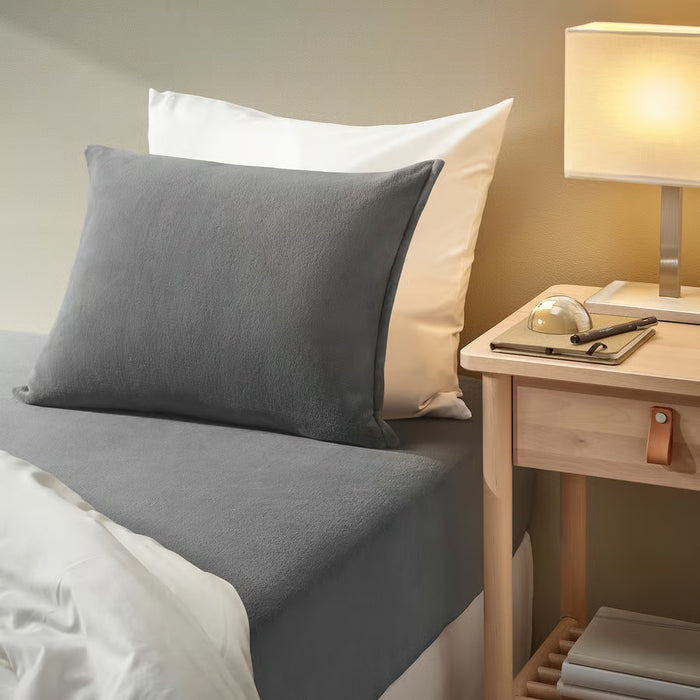 IKEA KRANSSALVIA grey fleece fitted sheet on cosy bed with pillows and bedside lamp