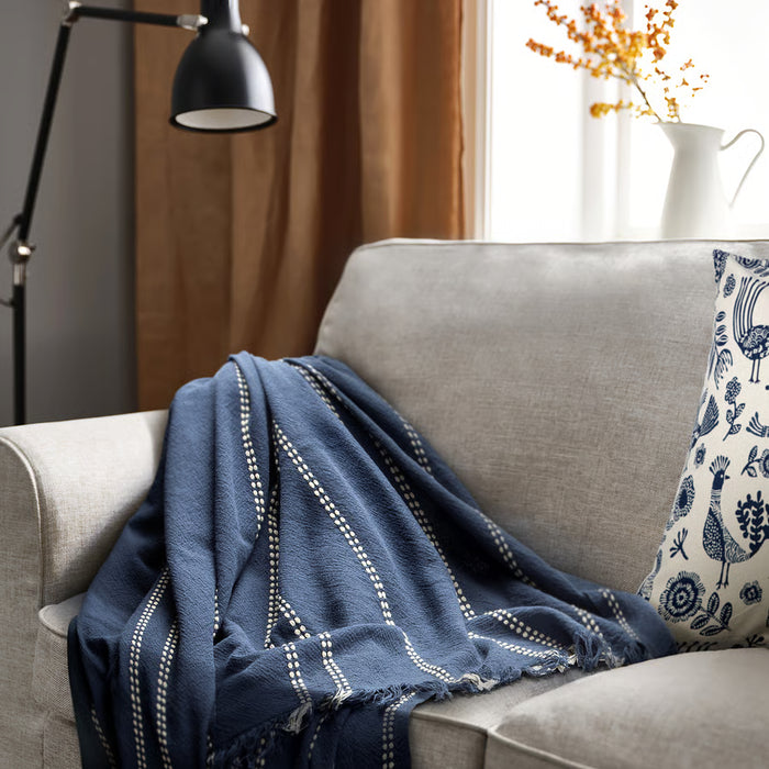 IKEA KRUTBRÄNNARE blue striped throw draped over grey sofa in styled living room setting