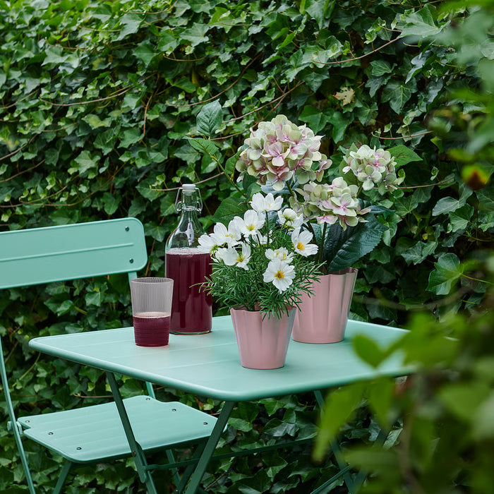 IKEA KVASTSPIREA pink plant pot styled with small green plant on a bright indoor shelf