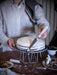 Person using IKEA LÄTTBAKAD offset spatula to cut a white frosted cake on a wire stand