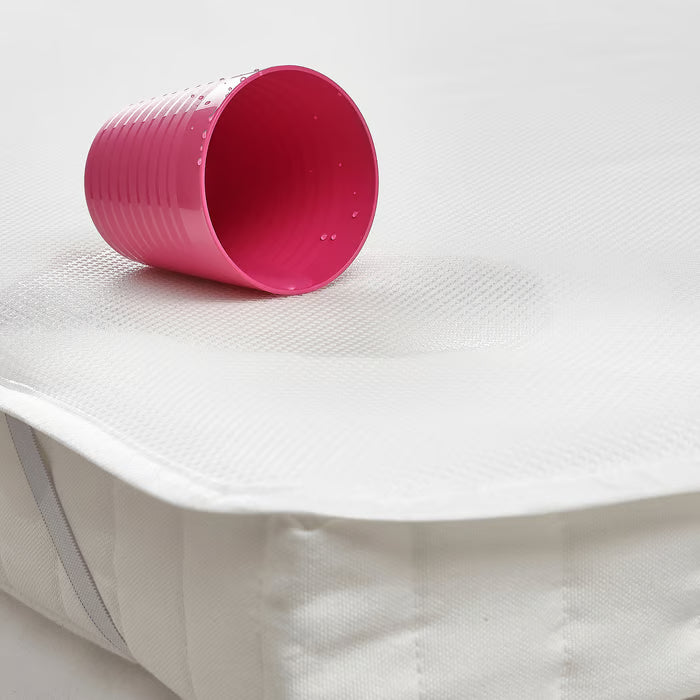IKEA LENAST waterproof mattress protector with pink cup spill demonstration showing liquid protection