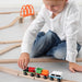 Child playing with IKEA LILLABO wooden train track and colourful carriages on floor