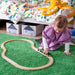 Toddler playing with IKEA LILLABO magnetic wooden train set on green rug imaginative floor play