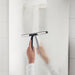 Person using IKEA LILLNAGGEN black squeegee to clean glass in a white bathroom