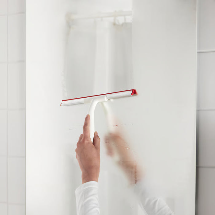 Person cleaning transparent shower glass door with IKEA LILLNAGGEN white and red squeegee