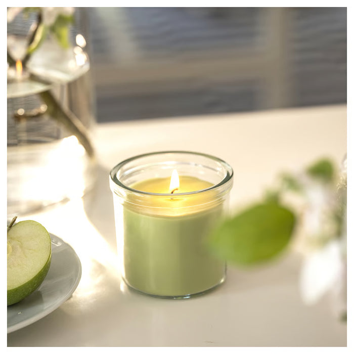 IKEA LÖVSKOGSLUND green scented candle glowing softly beside apple slices on table
