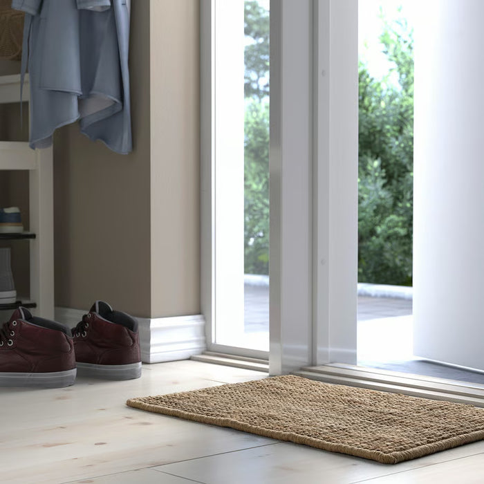 IKEA LOHALS jute door mat placed outside white entrance door with greenery