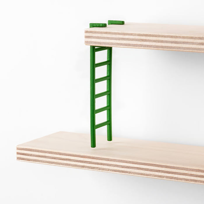 Close-up of IKEA LUSTIGT green plastic mini ladder resting on birch plywood shelf panel