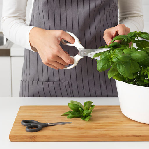  Person trimming fresh basil with IKEA MÄRKBART white kitchen scissors on a wooden cutting board
