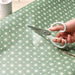 Person cutting green patterned paper with IKEA MÄRKBART scissors craft use close-up