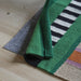 IKEA MÄVINN rug folded view green black white multicoloured stripe pattern on wooden floor