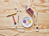 Child in yellow jacket painting on an easel with an IKEA MÅLA paintbrush