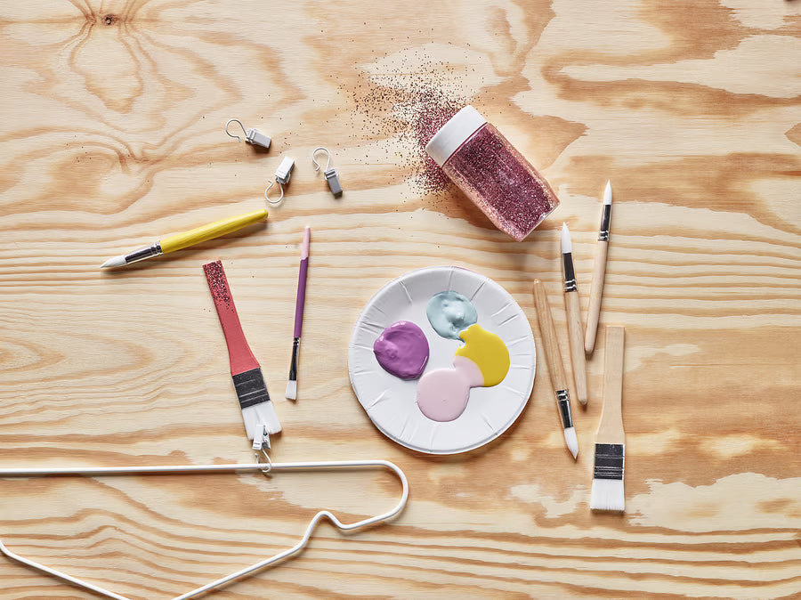 Child in yellow jacket painting on an easel with an IKEA MÅLA paintbrush