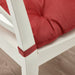 Red cushion on a white chair with a wooden floor background