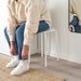  Person tying shoes while seated on IKEA MARIUS white stool showing everyday entryway use