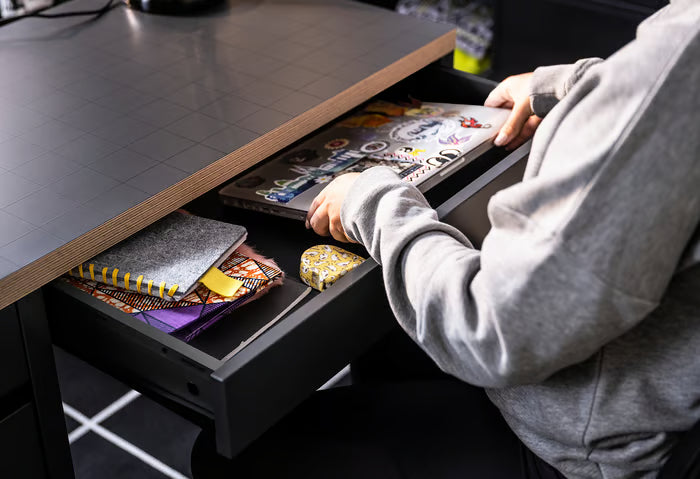 Open drawer of IKEA MICKE desk with notebooks and stationery organised inside