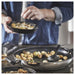 Home cook stirring food in IKEA MIDDAGSMAT frying pan on stovetop