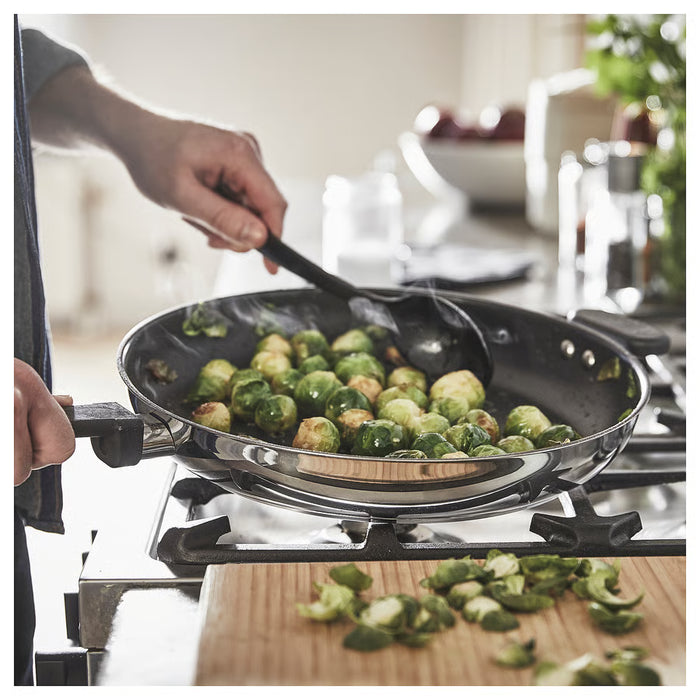 Person stirring brussels sprouts in IKEA MIDDAGSMAT frying pan on gas stove