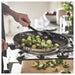 Person stirring brussels sprouts in IKEA MIDDAGSMAT frying pan on gas stove