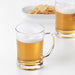 Two IKEA MJÖD beer tankards filled with beer on a table with snacks in background