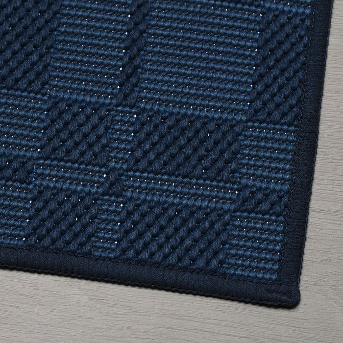 Close-up of IKEA NATTÅG dark blue check kitchen mat textured pattern on wooden floor