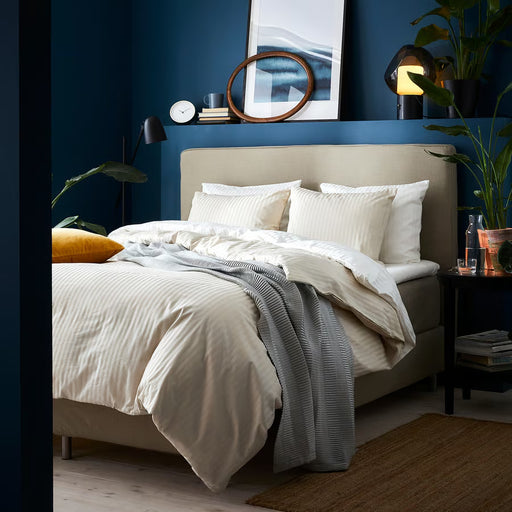 IKEA NATTJASMIN light beige duvet cover set styled on bed with teal walls and wooden bedside table
