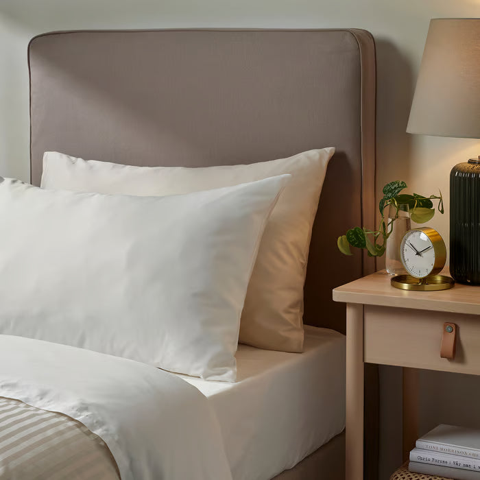 IKEA NATTJASMIN white pillowcases styled on bed with light wood bedside table lamp and plant