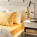 IKEA NATTJASMIN yellow sheet displayed on a bed with decorative pillows-70500674