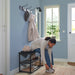 Person sitting on IKEA NIPÅSEN black bench tying shoes with coat and hat on hooks in hallway