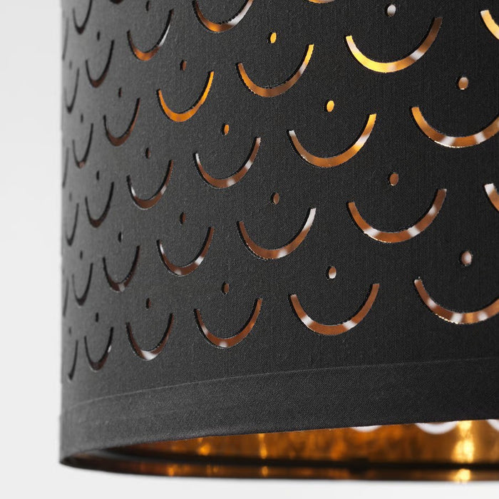 NYMÖ black lamp shade with brass trim hanging over a minimalist dining table in a bright Scandinavian interior.