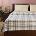 IKEA ODENSLÄTA plaid blanket on bed with pillows, side table, lamp and books