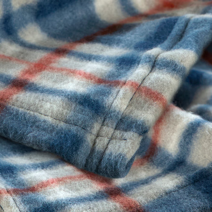 Close-up of IKEA ODENSLÄTA blanket showing blue, white and red check pattern and soft fabric texture