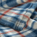 Close-up of IKEA ODENSLÄTA blanket showing blue, white and red check pattern and soft fabric texture