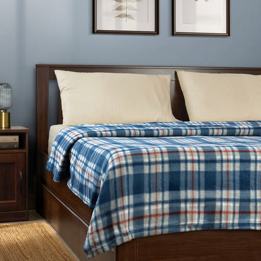 IKEA ODENSLÄTA blue and white check blanket on bed with white pillows and bedside table with lamp